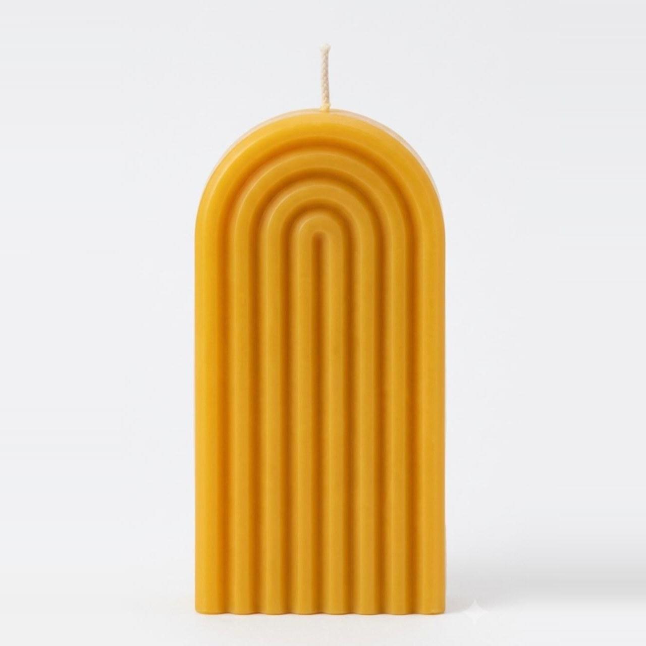 Stick Candle, a honey-yellow ribbed arch candle, against a plain background